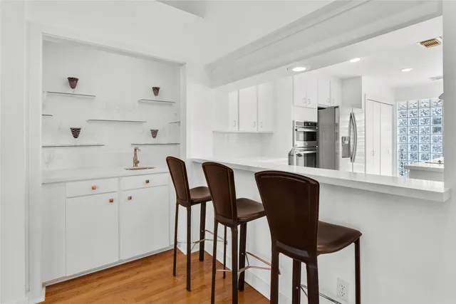 a kitchen with stainless steel appliances granite countertop a table chairs and a refrigerator