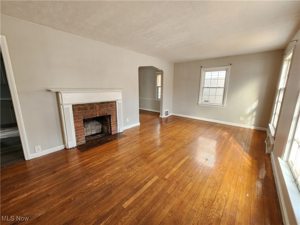 1160 Brentwood Road Cleveland, OH 44121 - Photo 5 of 26 Unfurnished living room featuring hardwood flooring, a fireplace, and a textured ceiling