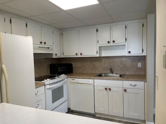 323 Tuscany Lane, Unit F Delray Beach, FL 33446 - Photo 4 of 12 a kitchen with white cabinets and white appliances