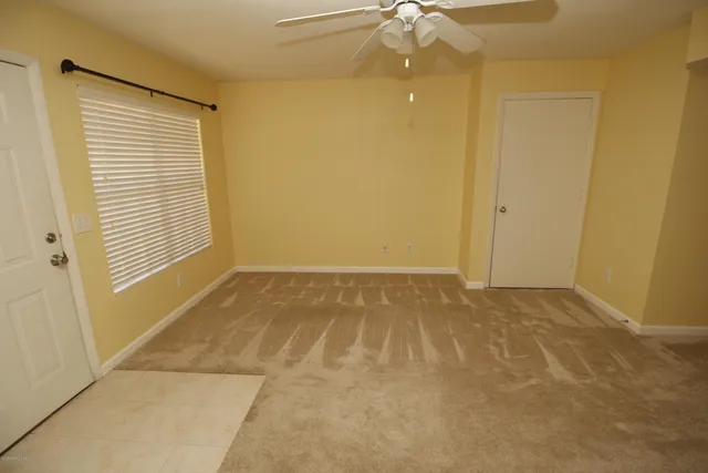 an empty room with a ceiling fan and carpet