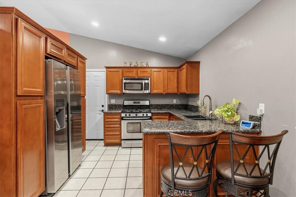 506 South Althea Avenue Rialto, CA 92376 - Photo 21 of 36 a kitchen with stainless steel appliances granite countertop a stove a sink dishwasher and a refrigerator with wooden floor