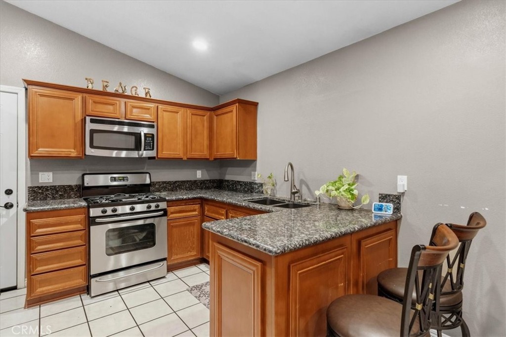 506 South Althea Avenue Rialto, CA 92376 - Photo 22 of 36 a kitchen with granite countertop a stove and a microwave
