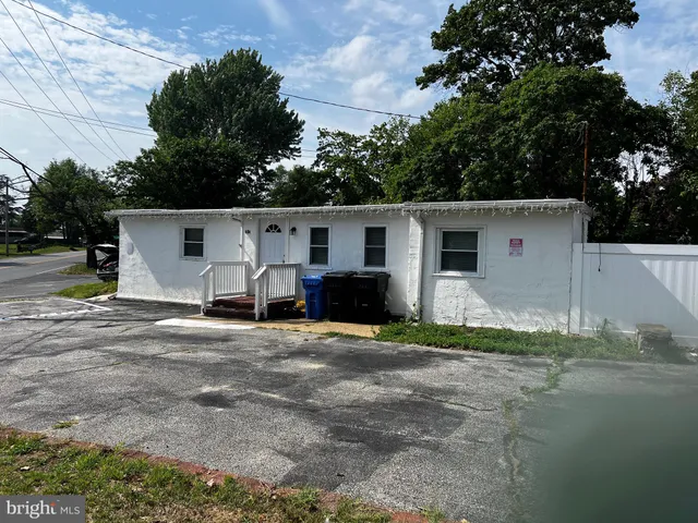 a view of a white house with a yard and large tree