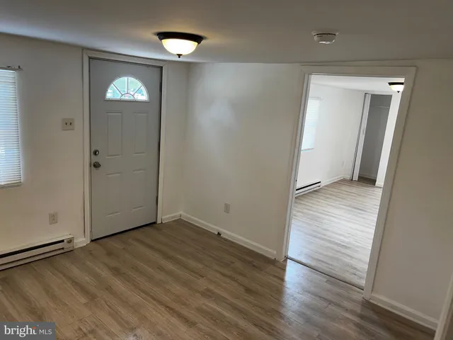 an empty room with wooden floor and a hallway