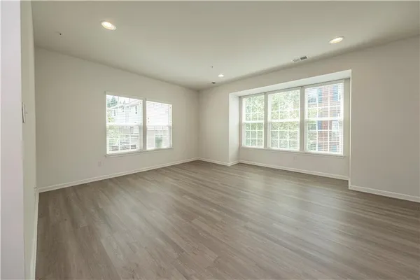 an empty room with wooden floor and windows