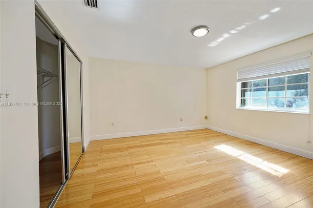 a view of empty room with wooden floor and fan