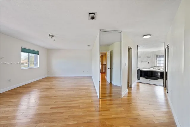 a view of a hallway with wooden floor a glass door and a bathroom