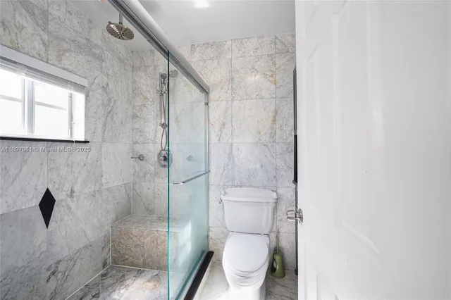 a white toilet sitting next to a shower