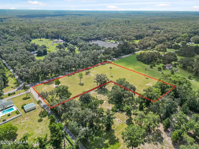 an aerial view of residential houses with outdoor space and trees