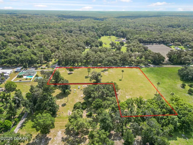 an aerial view of residential houses with outdoor space and trees