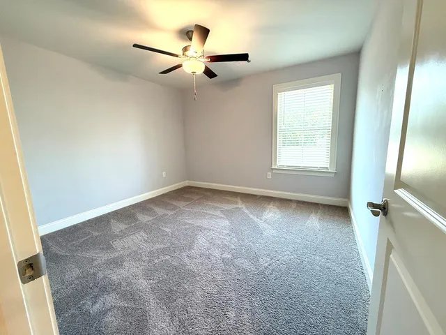 an empty room with windows and fan