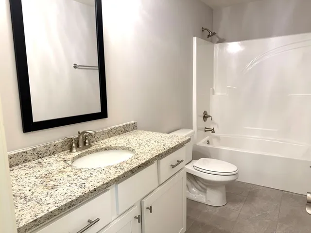 a bathroom with a granite countertop sink toilet mirror and shower