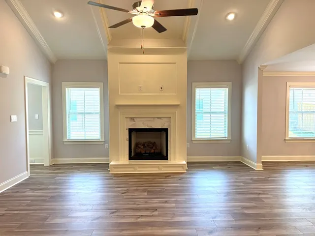 a view of an empty room with wooden floor fireplace and a window
