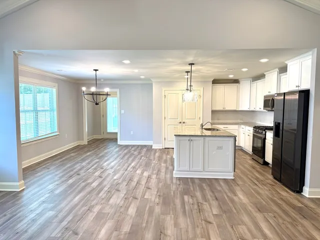 a large kitchen with a center island wooden floor stainless steel appliances and windows