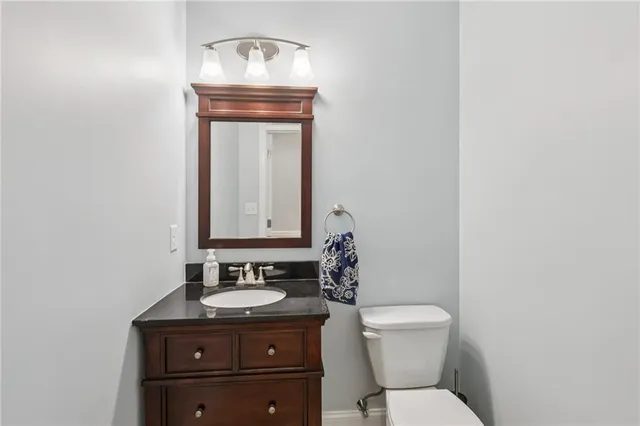 a bathroom with a granite countertop toilet a sink and a mirror