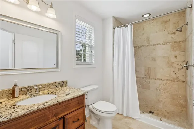 a bathroom with a granite countertop sink a toilet and shower