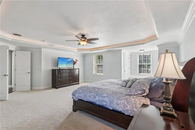 a bedroom with a large bed a flat tv screen and dresser