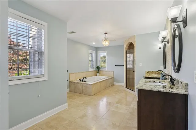 a spacious bathroom with a double vanity sink a mirror a bathtub and a shower