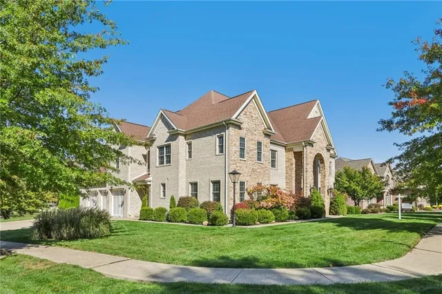a view of a white house with a big yard and potted plants and large trees
