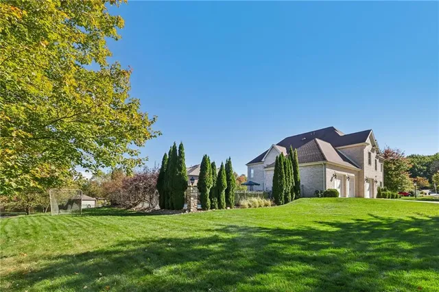 a view of a house with a big yard and large trees