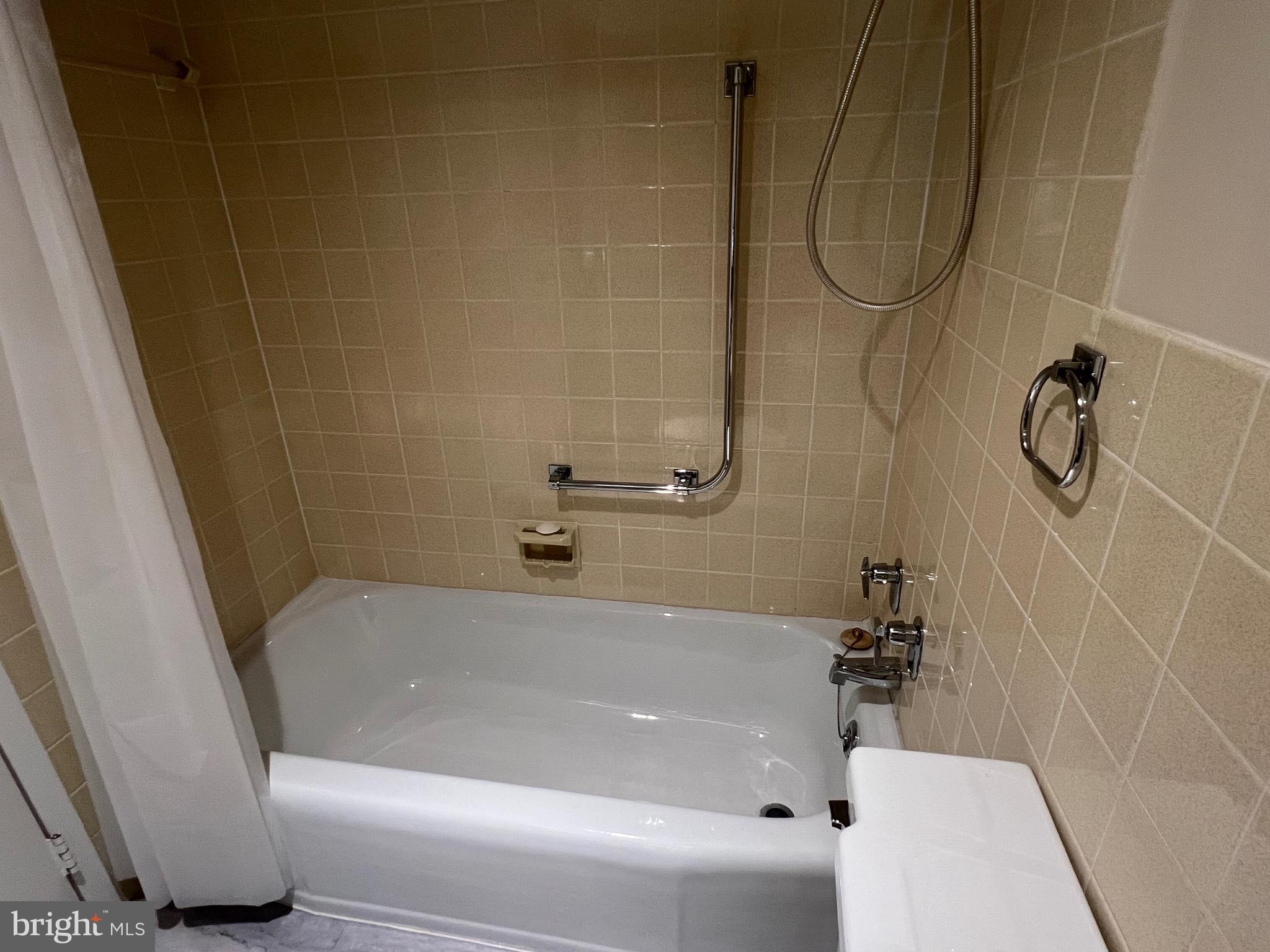 4401 Roland Avenue, Unit 402 Baltimore, MD 21210 - Photo 34 of 43 a bath tub sitting next to a white sink and a shower