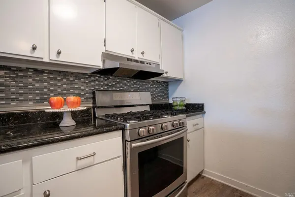 a kitchen with a refrigerator a stove top oven and wooden floor