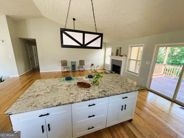 a kitchen with stainless steel appliances granite countertop a stove a sink dishwasher and white cabinets with wooden floor