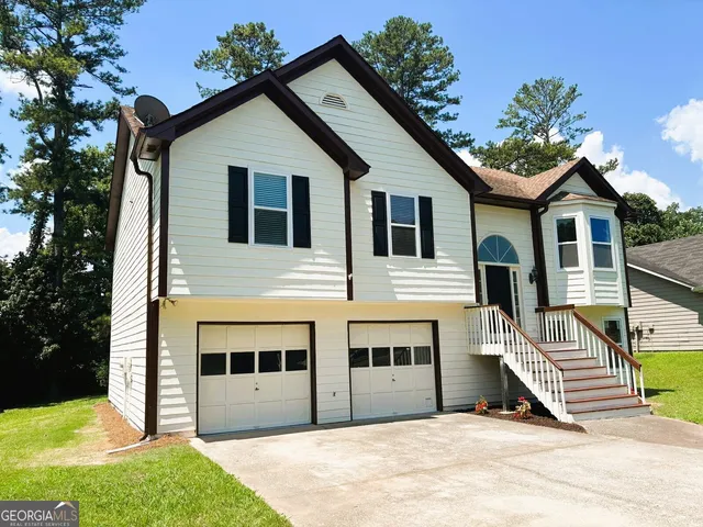 a view of a white house with a yard and potted plants