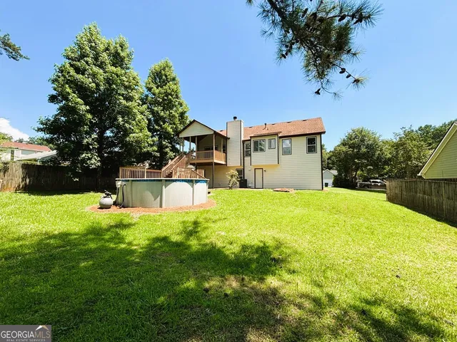 a view of a swimming pool with a patio and a yard