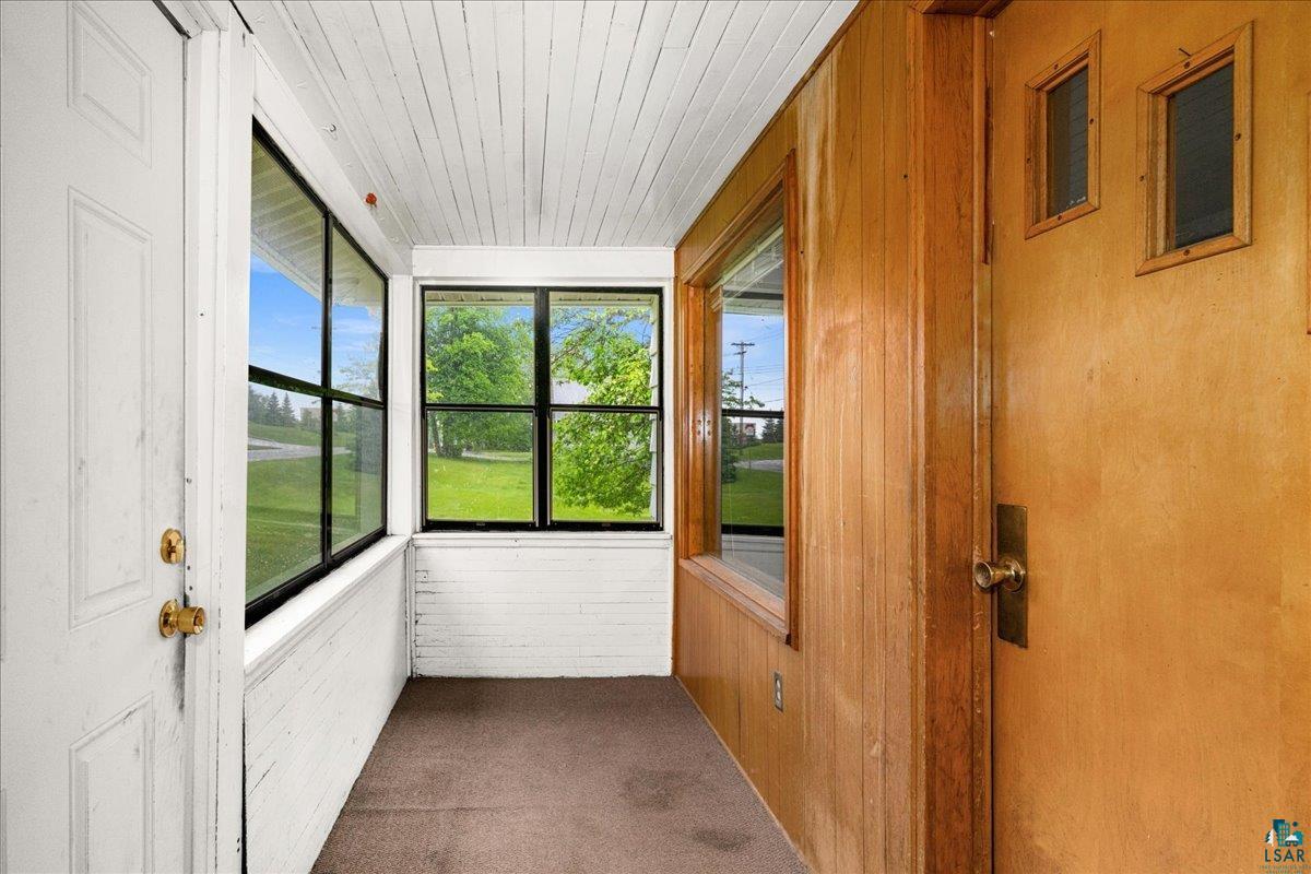 424 East Upham Road Duluth, MN 55811 - Photo 20 of 38 Enclosed porch featuring a white painted brick half-wall, black-framed windows, and a carpeted floor