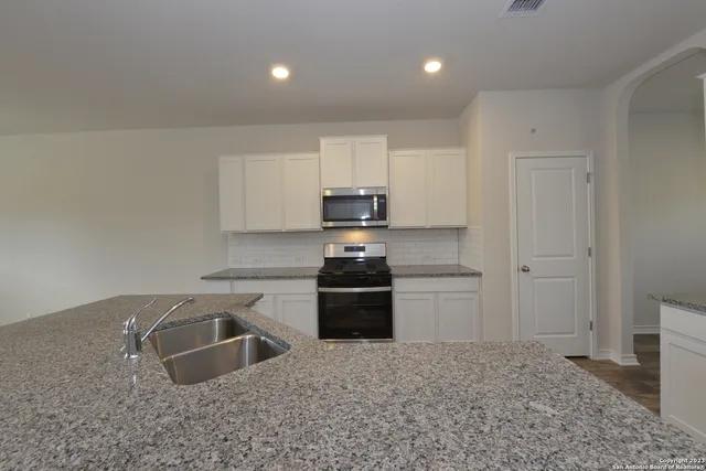 a kitchen with granite countertop white cabinets and stainless steel appliances