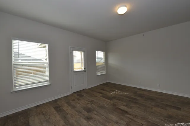 a view of an empty room with wooden floor and a window