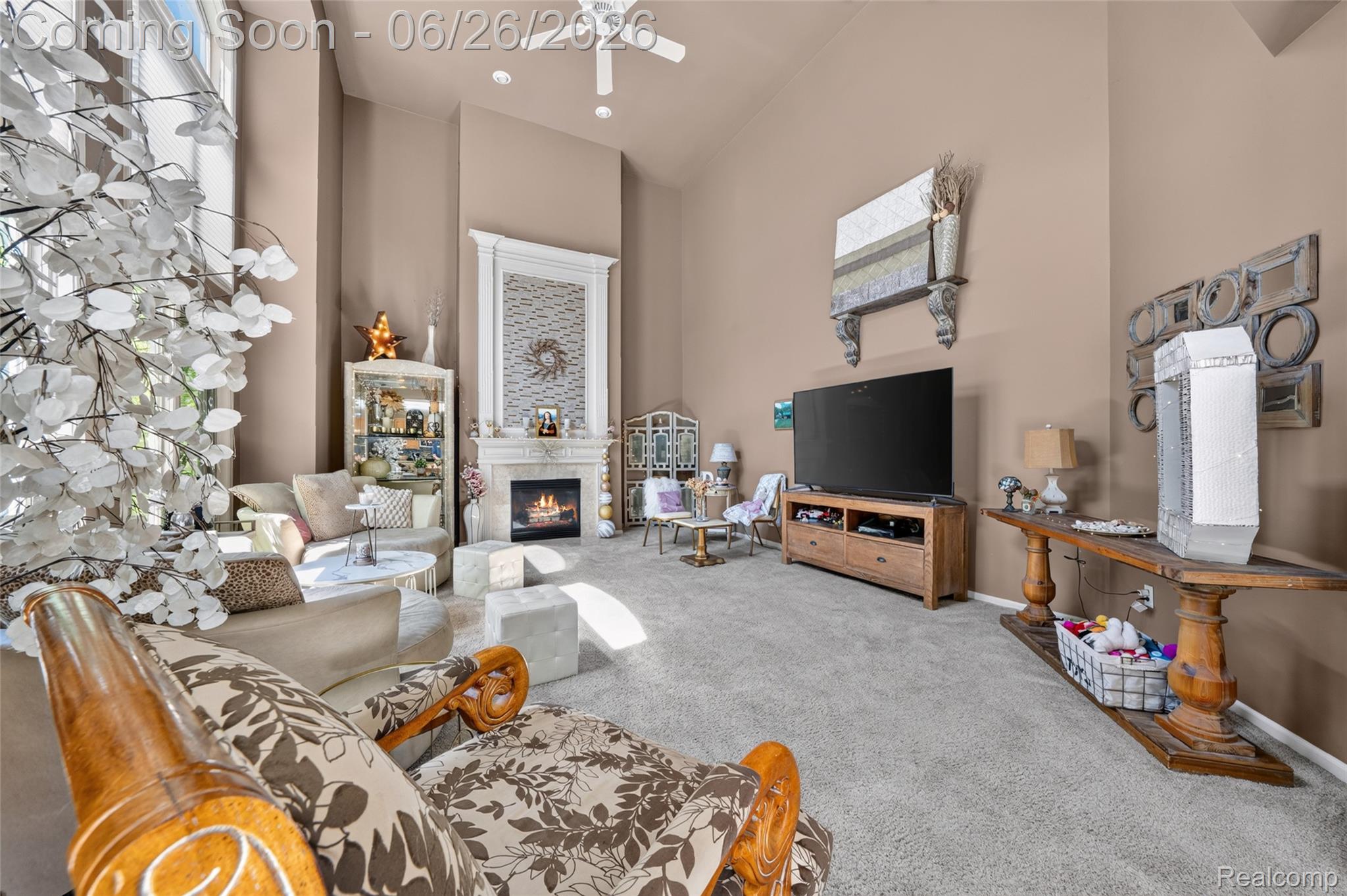 2619 Lambeth Park Rochester, MI 48306 - Photo 29 of 71 Vaulted ceiling living area featuring a prominent fireplace with a decorative mantel, large windows, ceiling fan, and carpeted flooring