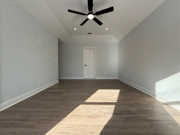 an empty room with wooden floor and ceiling fan