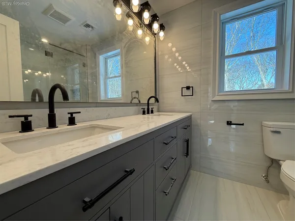 a bathroom with a double vanity sink a toilet and a mirror