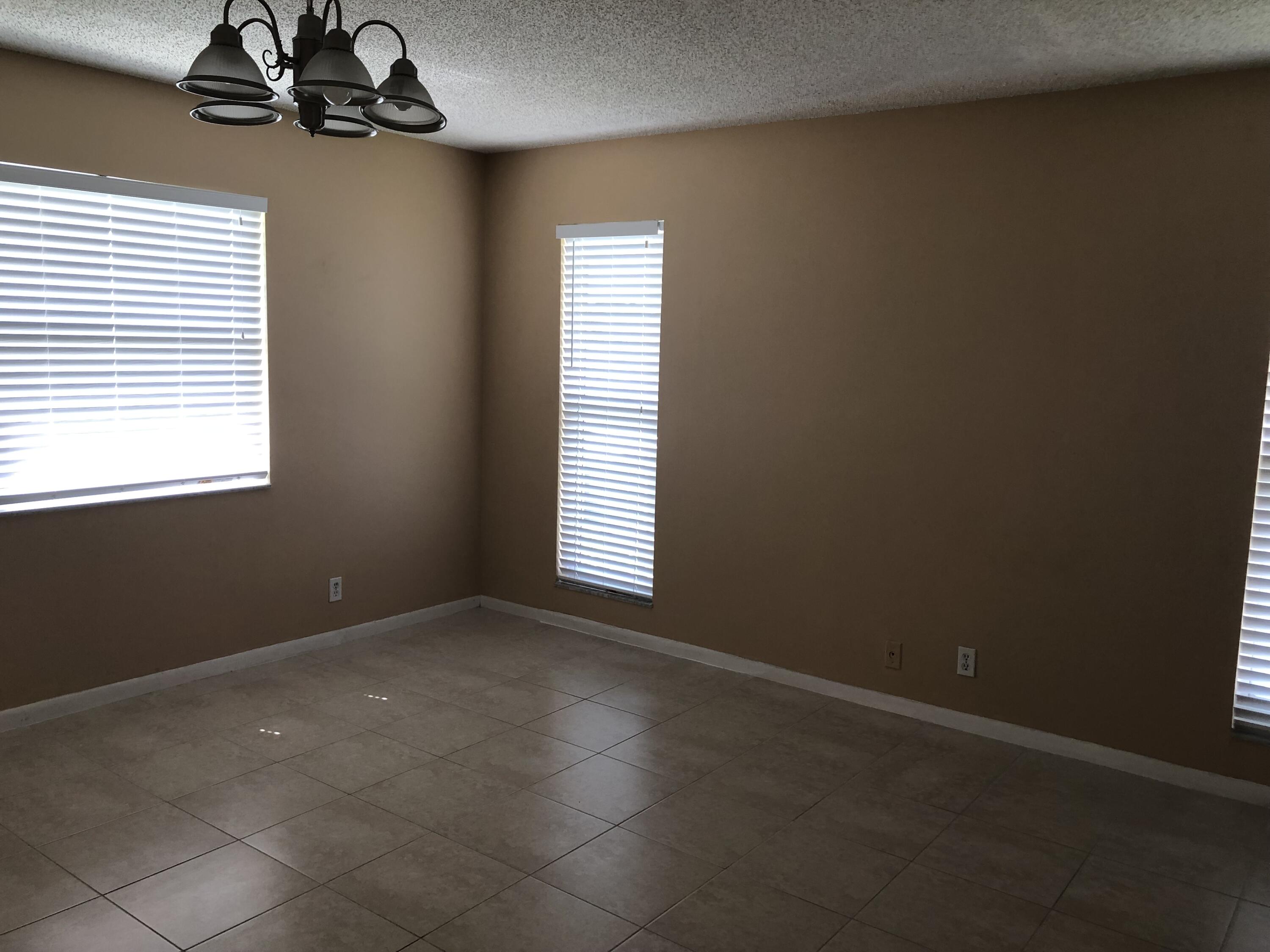 2500 Juniper Drive, Unit 204 Delray Beach, FL 33445 - Photo 8 of 9 an empty room with windows and chandelier fan