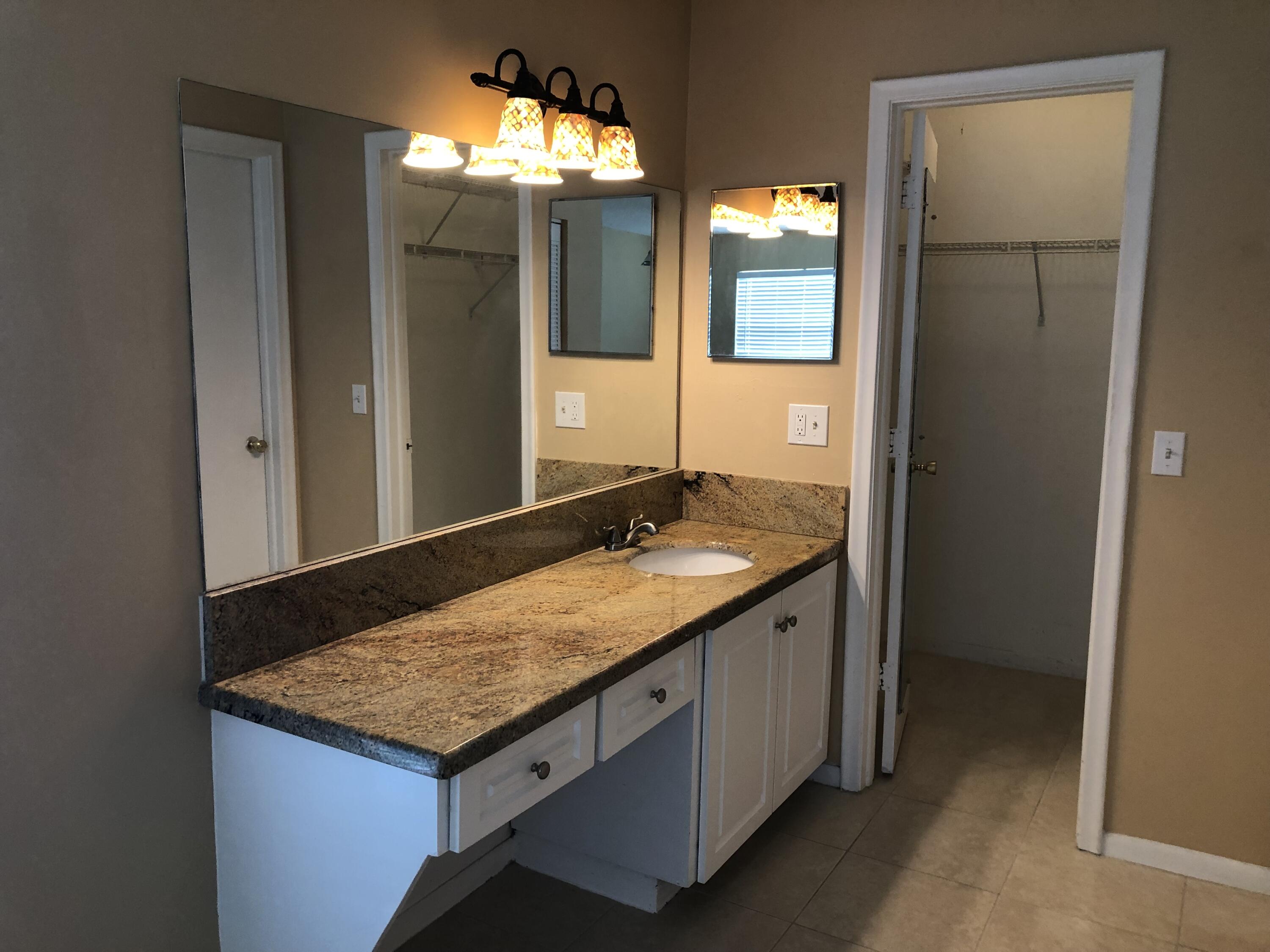 2500 Juniper Drive, Unit 204 Delray Beach, FL 33445 - Photo 9 of 9 a bathroom with a granite countertop sink and a mirror