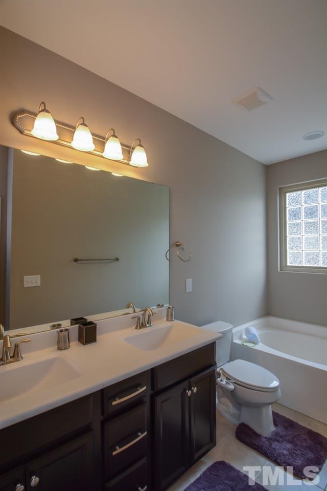697 Wickham Ridge Road Apex, NC 27539 - Photo 15 of 25 a bathroom with a toilet sink and mirror