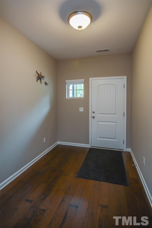 697 Wickham Ridge Road Apex, NC 27539 - Photo 3 of 25 an empty room with wooden floor and windows