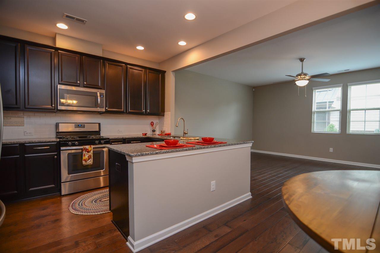 697 Wickham Ridge Road Apex, NC 27539 - Photo 4 of 25 a kitchen with kitchen island granite countertop wooden cabinets a stove and a oven