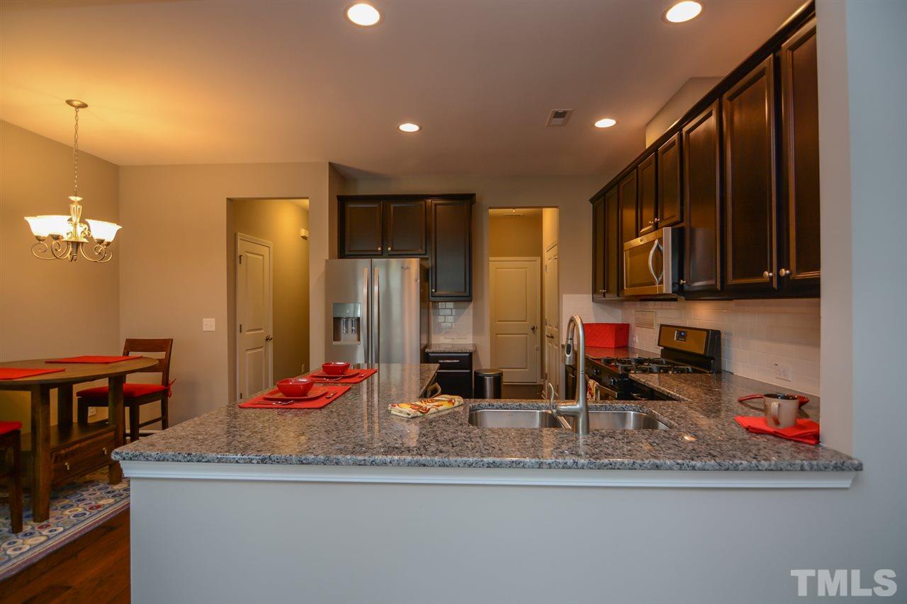 697 Wickham Ridge Road Apex, NC 27539 - Photo 7 of 25 a kitchen with stainless steel appliances granite countertop a sink and cabinets