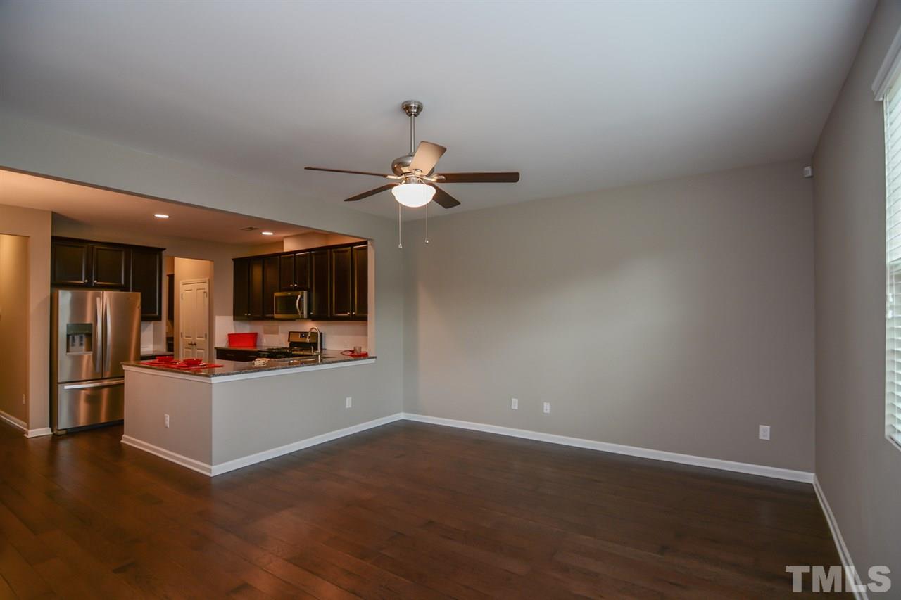 697 Wickham Ridge Road Apex, NC 27539 - Photo 9 of 25 a view of a livingroom with wooden floor and a ceiling fan