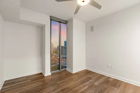 an empty room with wooden floor closet and windows