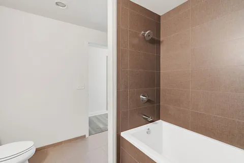 a bathroom with a granite countertop bathtub shower sink vanity and a toilet
