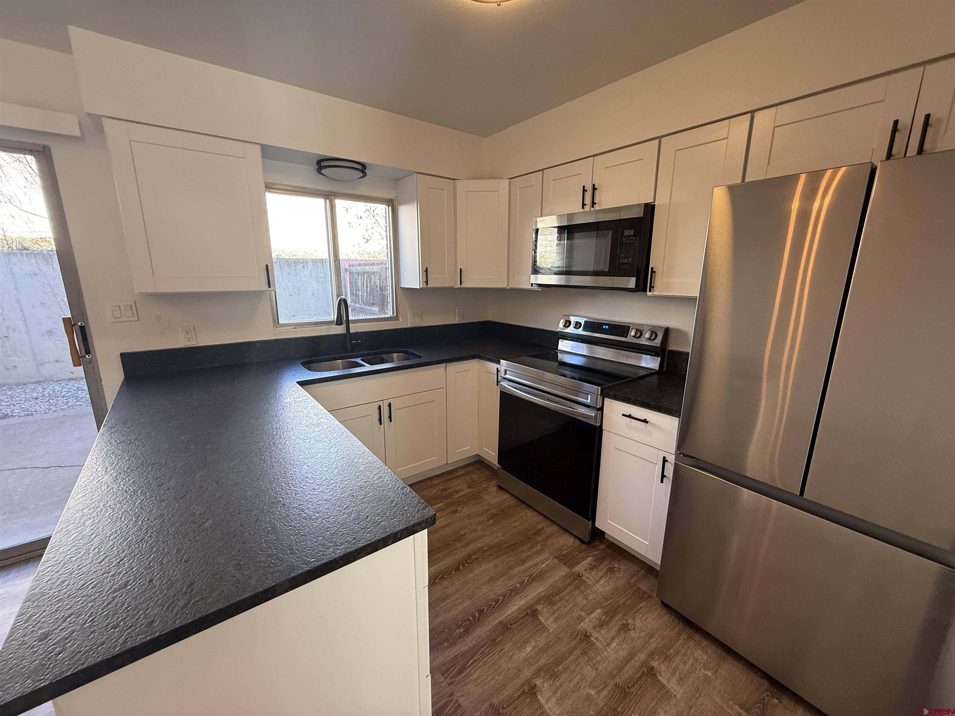 901 Florida Road, Unit 6 Durango, CO 81301 - Photo 17 of 21 a kitchen with granite countertop stainless steel appliances a refrigerator a sink a stove a microwave and cabinets