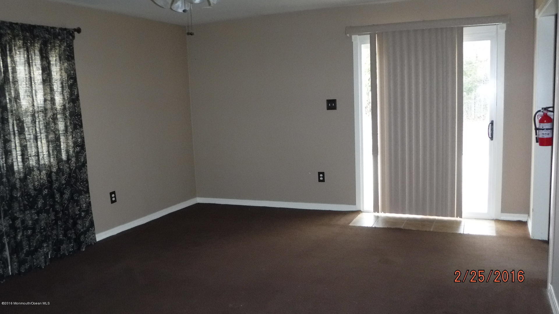 108 Toggle Road Manahawkin, NJ 08050 - Photo 8 of 11 an empty room with wooden floor and windows with curtains