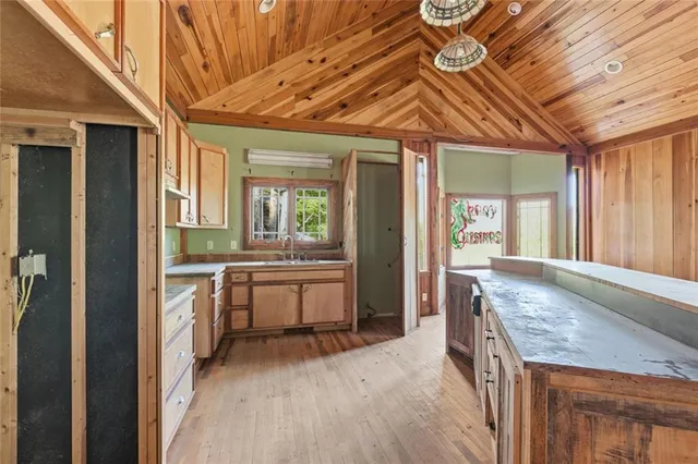 a view of an empty room with a window and a kitchen area