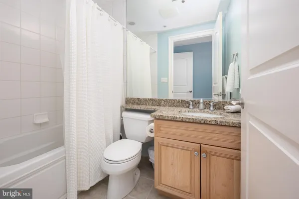 a bathroom with a granite countertop toilet a sink and a mirror