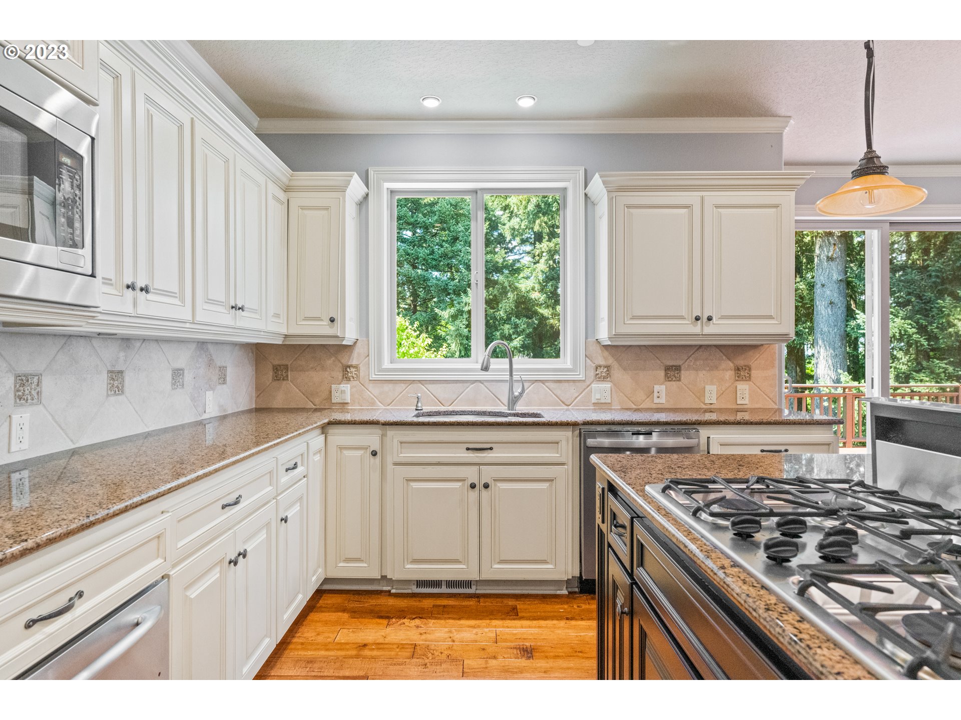18281 Southwest Florendo Lane Beaverton, OR 97007 - Photo 16 of 47 a kitchen with stainless steel appliances granite countertop a stove a sink and a white cabinets with wooden floor