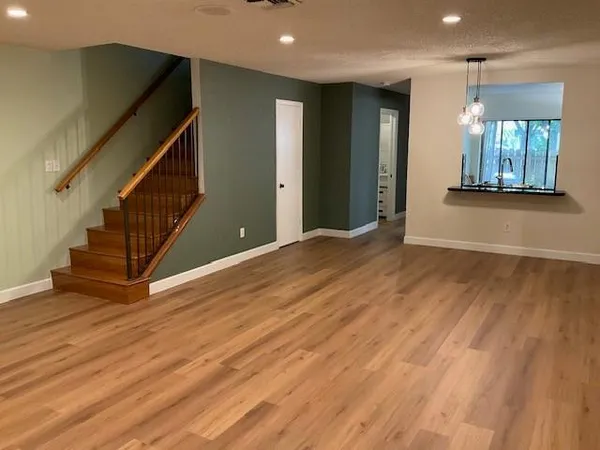 a view of an empty room with wooden floor and a chair